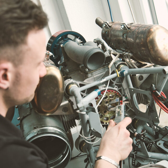 A Hirth technician using a digital caliper to perform high-precision measurements on an aircraft engine component
